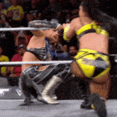 two women are wrestling in a ring with one wearing a pair of yellow shorts that say ' smackdown ' on them