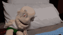 a stuffed baby is laying on a bed with a white pillow