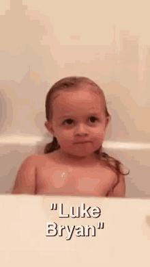 a little girl is taking a bath with the name luke bryan on the bottom
