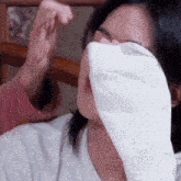 a woman covering her face with a white cloth with chinese writing on the bottom