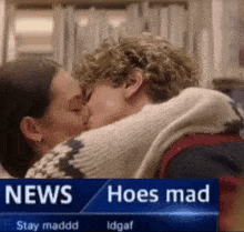 a man and a woman are kissing in front of a news report that says hoes mad