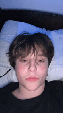 a young man is laying on a bed with a pillow on his head