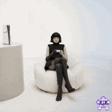 a woman sits in a bean bag chair holding a video game controller in front of a blue wall that says look at lalisa