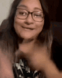 a woman wearing glasses is making a funny face and giving a thumbs up .
