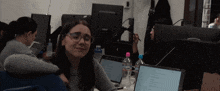 a woman wearing glasses sits at a desk in front of a dell monitor