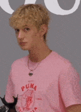 a man wearing a pink puma t-shirt and a necklace