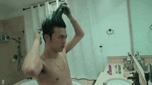 a shirtless man washing his hair in the bathroom