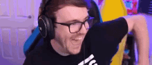 a man wearing glasses and headphones is sitting in a chair and smiling .