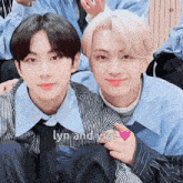 a couple of young men are sitting next to each other with a heart on their chests .