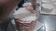 a cake is being decorated with pink frosting and the words made in animatica are visible in the corner