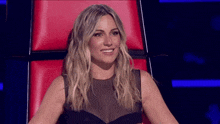 a woman is sitting in a red chair smiling