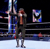 a wrestler stands in a ring with his arms outstretched in front of a sign that says logan