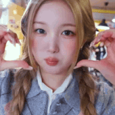 a girl with blonde hair is making a heart with her hands