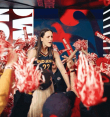 a woman wearing a jersey that says indiana 22 stands in front of a crowd