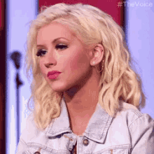 a close up of a blonde woman wearing a denim jacket .