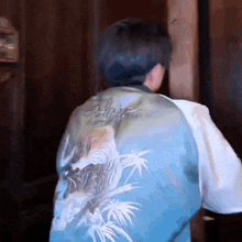 a man wearing a blue jacket with a tiger on the back is standing in a doorway .