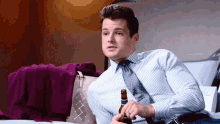 a man sitting on a bed with a bottle of beer