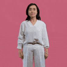 a woman in a white shirt and white pants is standing with her hands outstretched