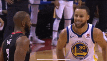 a basketball player wearing a golden state warriors jersey stands next to another player .