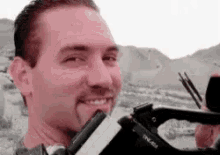a man is holding a camera in his hand and smiling at the camera .