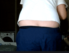 a person wearing a white shirt and blue shorts stands in front of a samsung washing machine