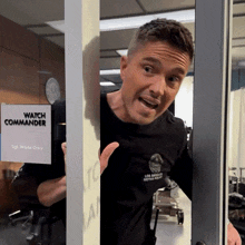 a man in a black shirt is standing in front of a watch commander sign