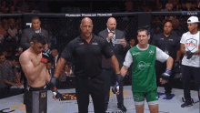 a man in a green shirt stands in a boxing ring with a referee