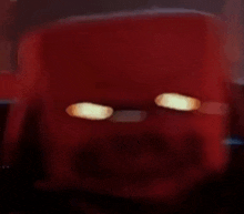 a close up of a red cube with glowing eyes .