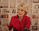 a woman in a red shirt is looking at a tablet