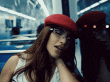 a woman wearing a red hat and glasses has a tattoo on her wrist that says ' u.s.a. '