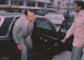 a man is getting out of a car while another man stands behind him