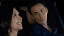 a woman sitting in the back seat of a car with a man holding a remote control