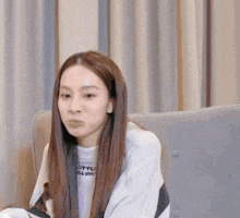 a young woman is sitting on a couch making a funny face .