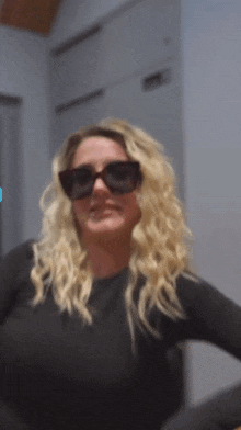 a woman is wearing sunglasses and a black shirt