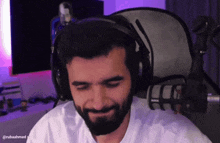 a man with a beard wearing headphones is sitting in front of a microphone