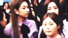 a group of young women are sitting in a crowd and one of them is wearing a purple shirt .