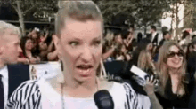 a woman is talking into a microphone at a red carpet event .
