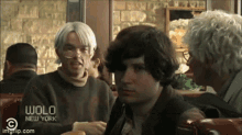 a group of people sitting at a table with wolo new york on the bottom