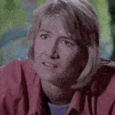 a woman with blonde hair and blue eyes is wearing a pink shirt and earrings