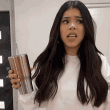 a woman with long hair is holding a stainless steel cup with a straw .