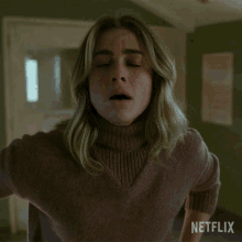 a woman in a brown sweater with netflix written on the bottom right