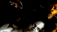 a man with a beard is holding another man 's head in a dark room