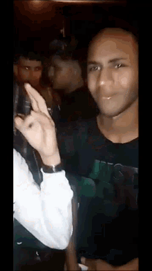 a man in a black shirt is standing in a crowd of people in a dark room .