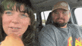 a man and a woman are sitting in a car and the man is wearing a gorilla wear gym hat