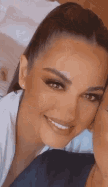 a close up of a woman 's face with a ponytail smiling .