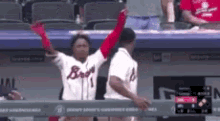 a baseball player wearing a braves jersey is raising his arms in the air