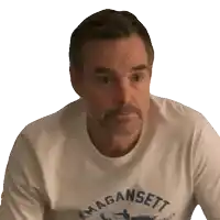 a man wearing a magaansett t-shirt is looking at the camera