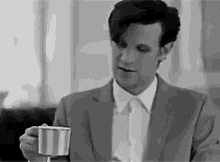 a man in a suit and tie is holding a striped cup