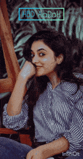 a woman in a striped shirt is sitting in a chair with her hand on her face