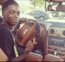 a young man sitting in a bentley car giving a middle finger